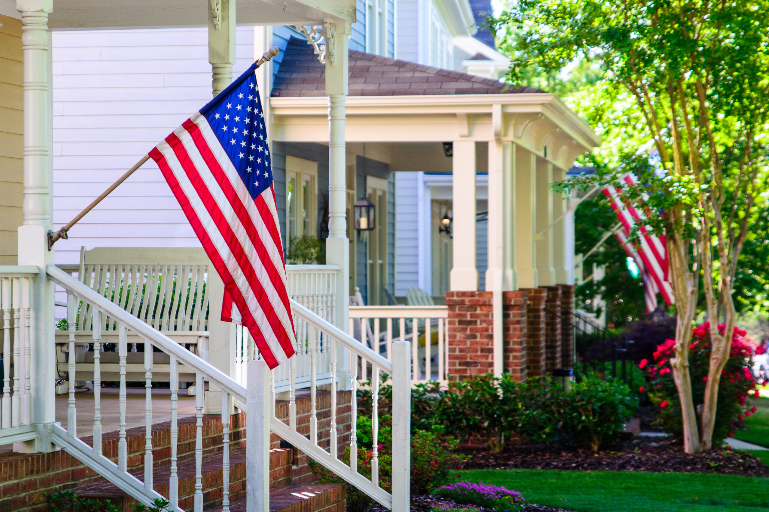 A line of suburban homes display large American Flags