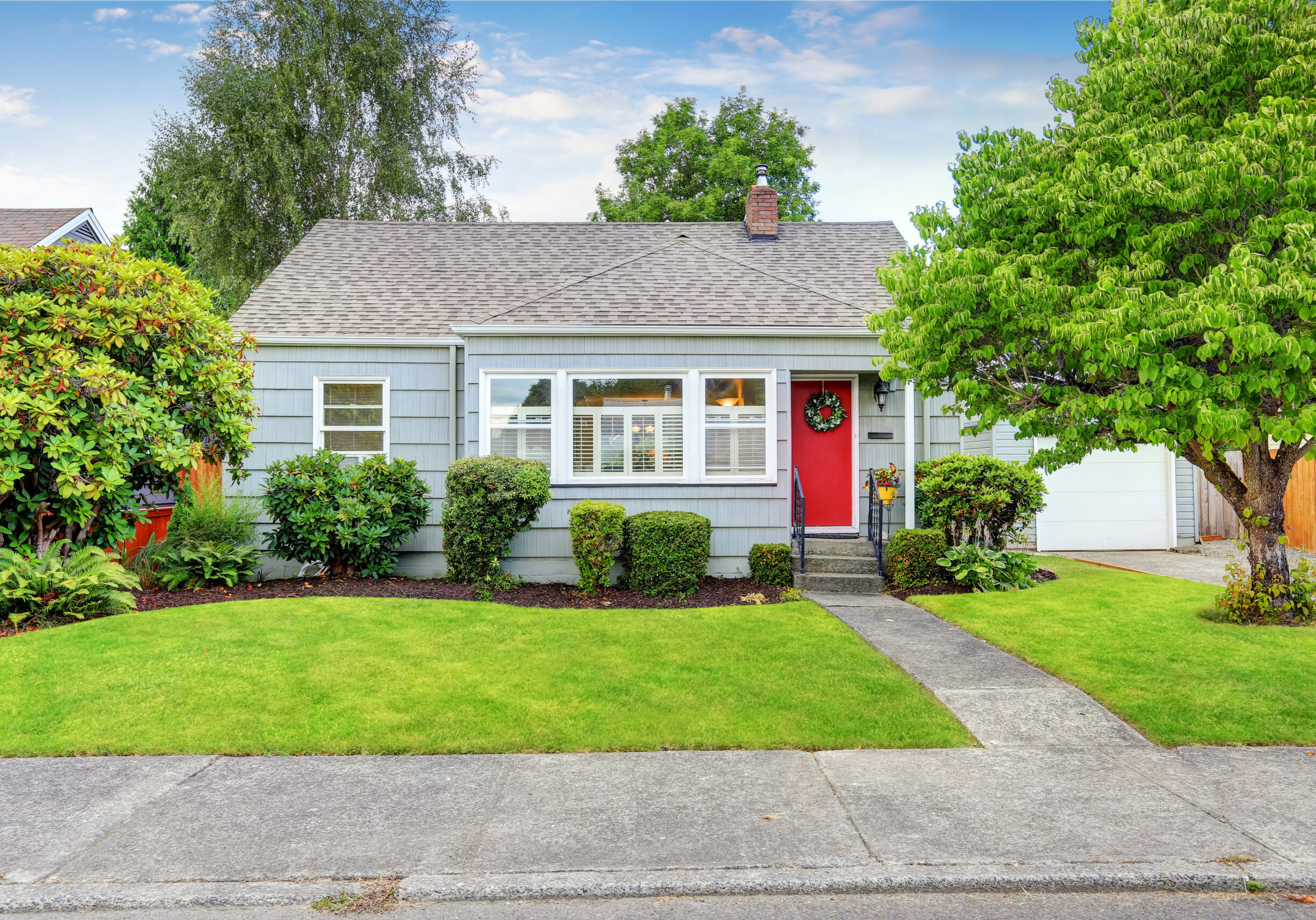 Exterior of small American house with blue paint and red entrance door. Northwest, USA